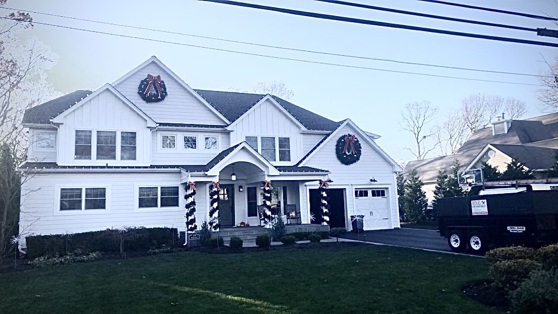 Large white colonial home with gable dormers and a covered entry on Long Island